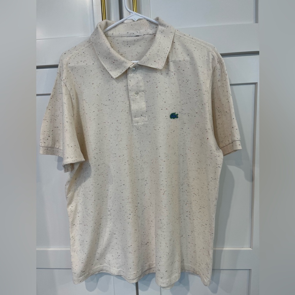 Lacoste Polo speckled primary color threads on cream polo.